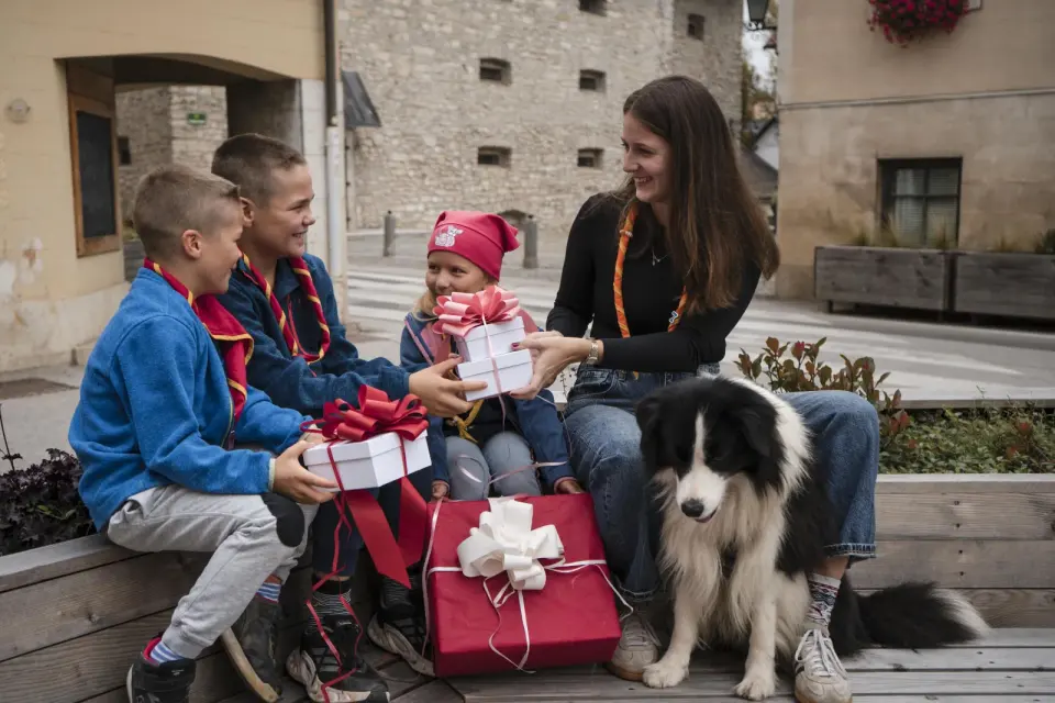 Mladi taborniki z zavitimi darili in psom med oddajo daril